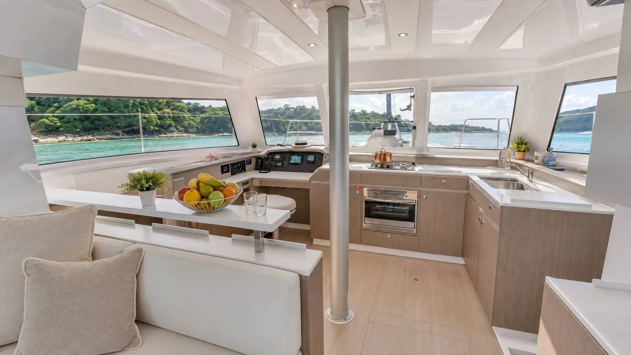Bright catamaran saloon with galley, dining area and panoramic windows over the sea